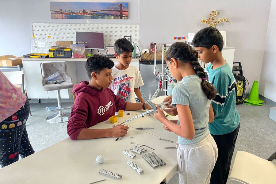 Campers building a robot chassis with tools on a work table