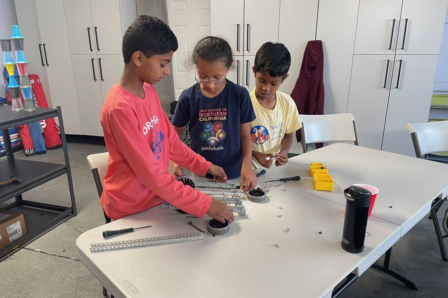 Campers building robots together at a work table during the summer camp