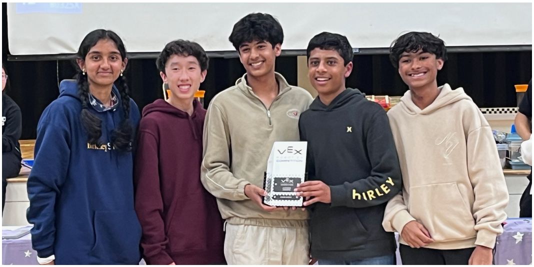 Five Rogue Robotics members holding a VEX award after a competition