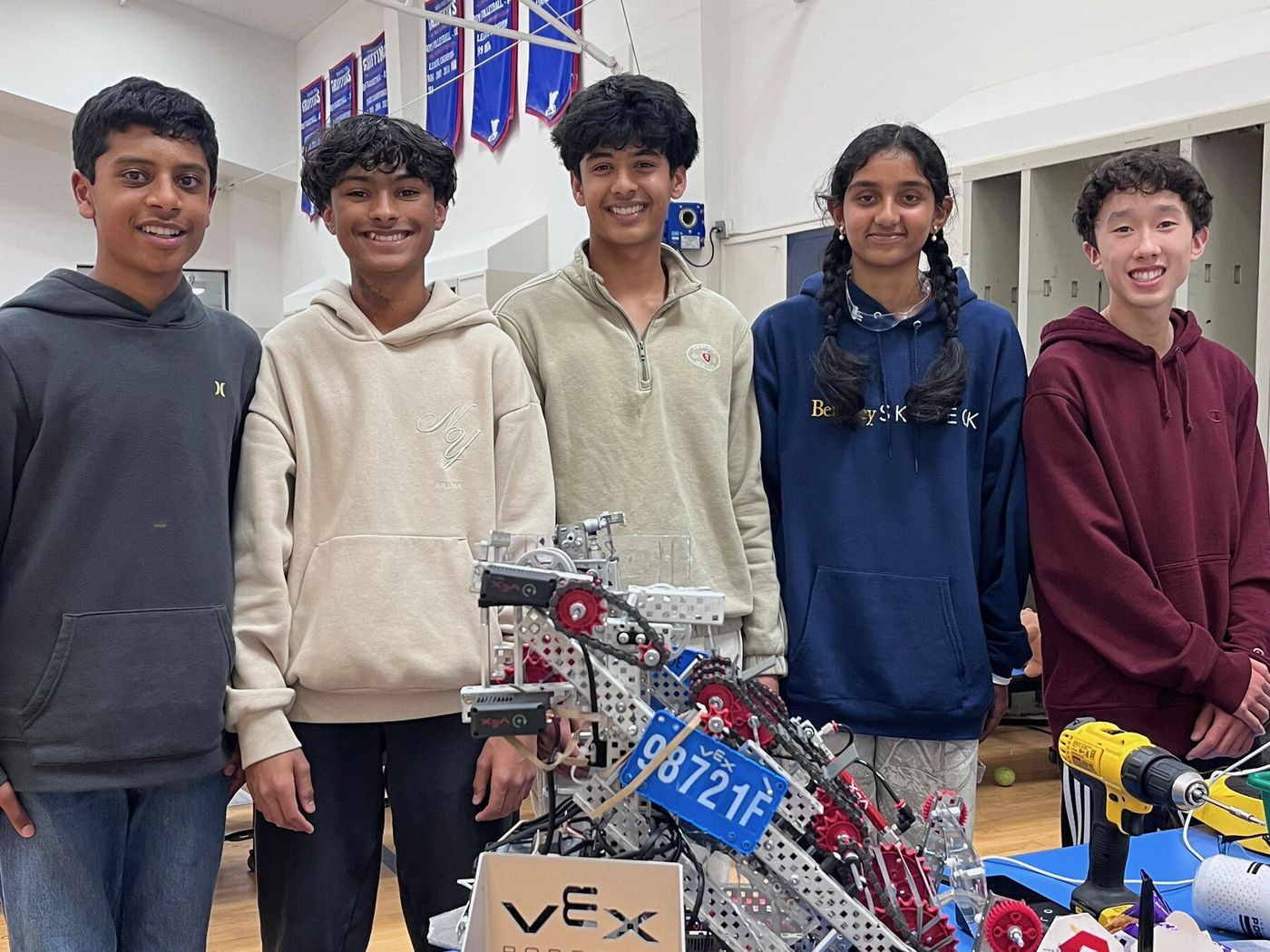 Team members standing behind the 98721F robot in the pits with tools on the table