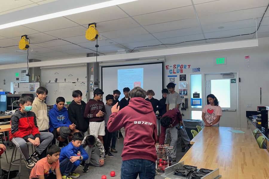 A crowd of students kneeling around the robot as it drives