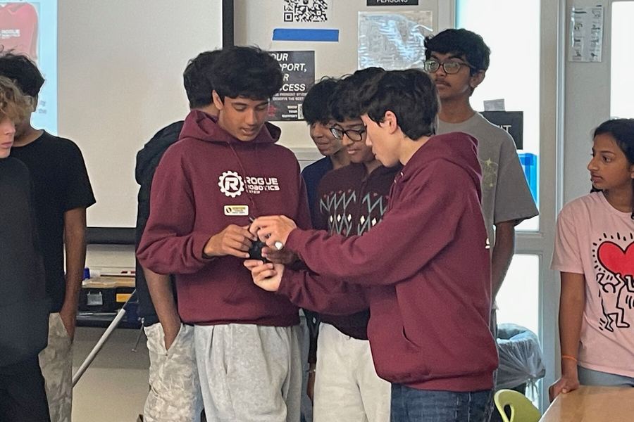 Team members presenting robotics to a middle school audience